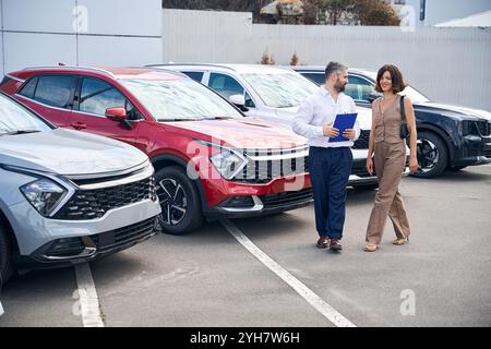 Une cliente discutant avec le directeur des ventes dans le salon de l'automobile à l'extérieur Banque D'Images