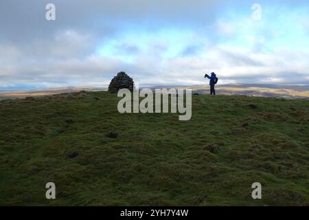 Homme (randonneur) prenant une photo du grand Cairn de pierre sur le sommet de 'Elbolton' (Coral Reef Knoll) près de Wharfedale, Yorkshire Dales National Park, Royaume-Uni. Banque D'Images