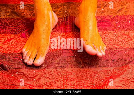 Cérémonie traditionnelle de mariage indien Haldi - pâte jaune appliquée sur les pieds du marié pour les bénédictions Banque D'Images