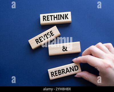 Repenser réviser et changer de marque symbole. Blocs en bois avec les mots Rethink réviser et rebrand. Main d'homme d'affaires. Beau fond bleu profond. Entreprise et Banque D'Images