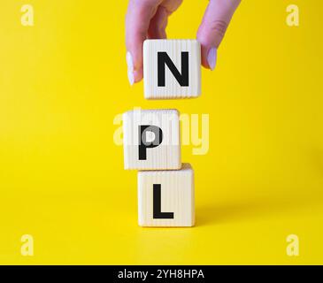 NPL - symbole de prêt non performant. Mot concept IPO sur cubes en bois. Main d'homme d'affaires. Beau fond jaune. Business et concept NPL. Copier spac Banque D'Images