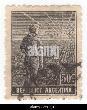 ARGENTINE - 1911 : 50 centavo timbre-poste noir représentant ouvrier agricole, composition allégorique Agriculture. Un jeune agriculteur avec une charrue au bord d'un champ partiellement labouré regarde le lever du soleil. Un symbole de la réforme agricole et de la formation de l'Argentine comme puissance mondiale dans la production agricole Banque D'Images