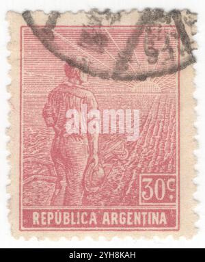 ARGENTINE - 1912 : 30 centavos Claret timbre-poste représentant ouvrier agricole, composition allégorique Agriculture. Un jeune agriculteur avec une charrue au bord d'un champ partiellement labouré regarde le lever du soleil. Un symbole de la réforme agricole et de la formation de l'Argentine comme puissance mondiale dans la production agricole Banque D'Images