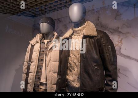 Deux mannequins présentent des vestes d'hiver à la mode et un pull chaud, mettant en valeur les tendances actuelles dans un cadre de magasin de détail Banque D'Images