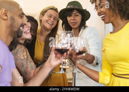 Groupe diversifié d'amis heureux célébrant ensemble à la fête à la maison, moment authentique de joie et de connexion avec les jeunes multiethniques Banque D'Images