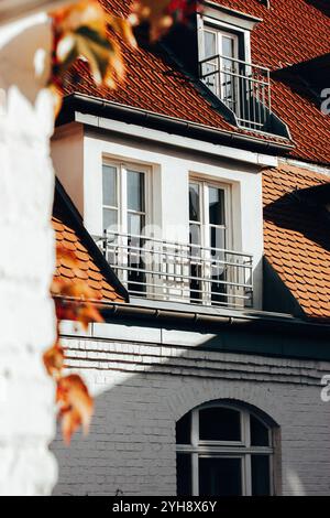 Balcon du bâtiment, façade en briques blanches et toit brun. Immeuble d'appartements avec balcon. Saison d'automne dans la ville. Immobilier urbain architecture européenne Banque D'Images