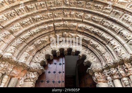 Une arche en pierre magnifiquement sculptée encadre les grandes portes en bois d'une ancienne église d'Obanos, mettant en valeur l'artisanat complexe. Banque D'Images