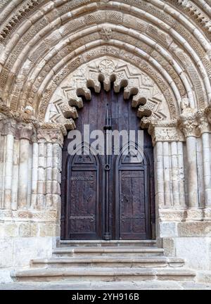 Une arche en pierre magnifiquement sculptée encadre les grandes portes en bois d'une ancienne église d'Estella, mettant en valeur l'artisanat complexe. Banque D'Images