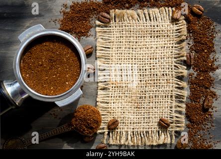 Cône de café avec du café moulu et des grains de café sur une table noire sur un fond de toile de jute. Banque D'Images