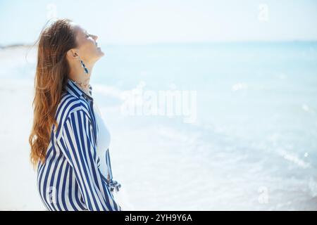 détendue élégante femme de 40 ans sur la rive de l'océan profitant de la tranquillité. Banque D'Images