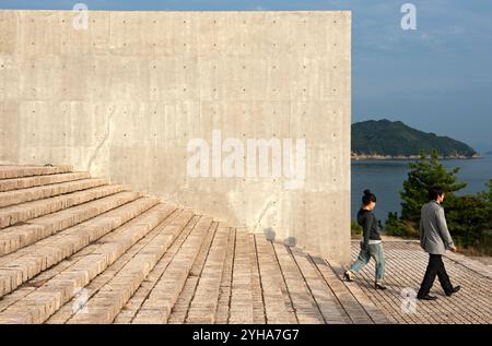 Les visiteurs descendent les marches à côté d'un mur de béton austère conçu par l'architecte Ando Tadao sur l'île d'art de Naoshima dans la mer intérieure de Seto, au Japon. Banque D'Images