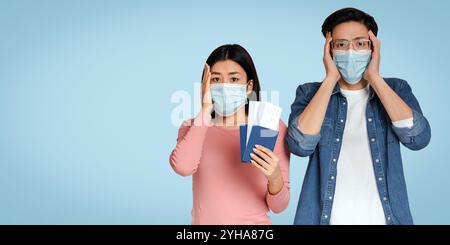 Couple chinois paniqué portant des masques médicaux Holding passeports et des billets Banque D'Images