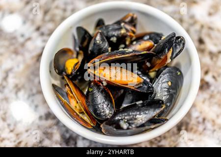 Moules à la sauce à l'ail bol cuit de plat de moules de fruits de mer préparé au dîner dans la plaque blanche macro gros plan, repas fait maison sur la table de la cuisine Banque D'Images