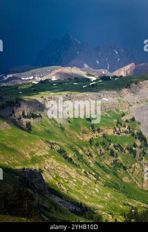 Un orage passe au-dessus des montagnes Teton alors que la lumière du soleil traverse et frappe le plateau du Death Canyon dans le parc national de Grand Teton, Wyoming. Banque D'Images