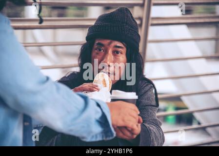 Femme aidant les mains aux sans-abri pauvreté mendiant homme tenant la main demandant l'argent travail et espérant de l'aide dans la ville sale impuissante assis dans les rues Banque D'Images