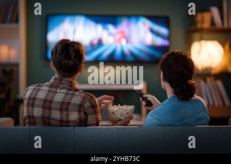 Famille heureuse regardant la télévision, films le soir à la maison. Couple passant du temps ensemble. Banque D'Images