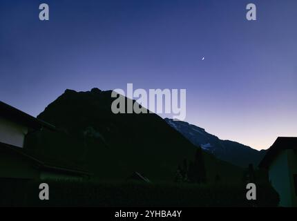 Lune dans le ciel au crépuscule au-dessus d'une montagne dans la ville de Golling an der Salzach, Autriche un soir d'été. Banque D'Images