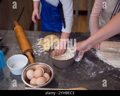 Enfant et femme préparant joyeusement la pâte à biscuits dans une cuisine chaleureuse, se liant par la cuisson, apprenant de nouvelles compétences et créant un concept de souvenirs chéris Banque D'Images