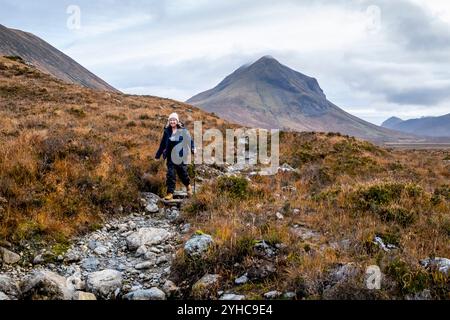 Une femme âgée faisant une randonnée à travers les Hiills/montagnes de Cuillin sur la promenade de Sligachan à Elgol, île de Skye, Écosse, Royaume-Uni. Banque D'Images