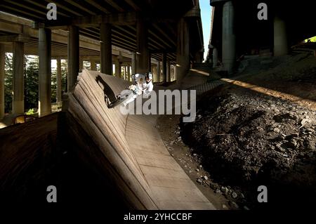 A male mountain biker riding on a wooden bank in the Colonnade Bike Park under the I-5 in Seattle, WA. Stock Photo