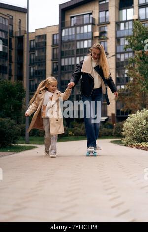 Sa fille apprend à sa mère à skateboard dans un parc de la ville Banque D'Images