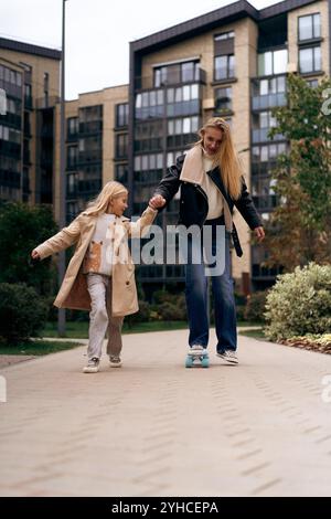 Maman et fille skateboard dans un parc de la ville Banque D'Images