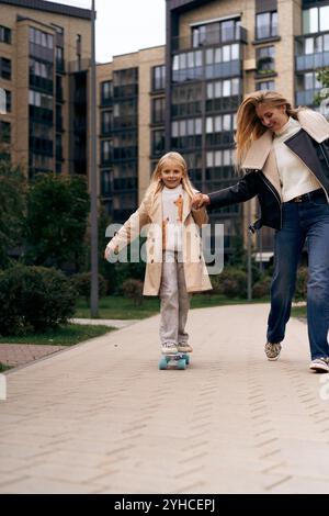 Maman et fille skateboard dans un parc de la ville Banque D'Images