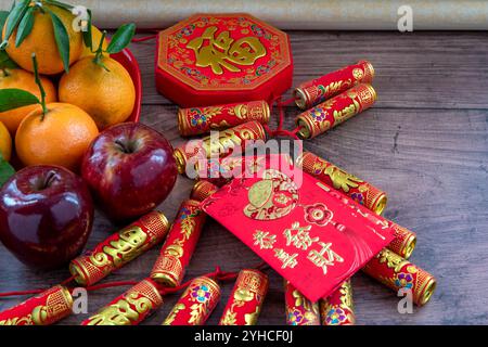 Gros plan d'une assiette de mandarines et de pommes rouges. Décorations lunaires du nouvel an et paquets rouges avec bonne fortune, santé, mots de richesse sur eux. A Chines Banque D'Images