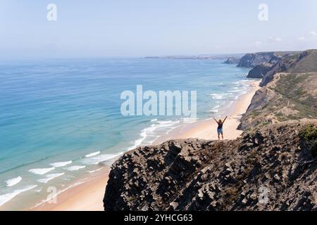 Silhouette d'une femme debout sur une falaise au-dessus de la plage de Cordoama, Portugal Banque D'Images