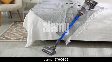 Un aspirateur sans fil reposant sur le lit à l'intérieur Banque D'Images