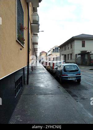 Turin, Italie - 18 octobre 2024 : rue d'un quartier ouvrier sous la pluie, avec des voitures garées. Banque D'Images