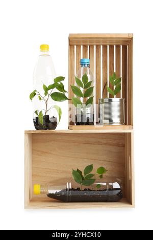 Concept de recyclage. Caisses en bois avec des plantes en bouteilles et canettes isolées sur blanc Banque D'Images