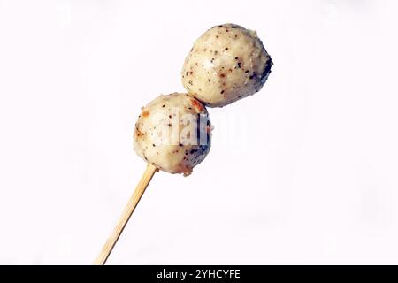 Boule de poisson au poivre noir japonais, boulette de poulet, boulette de viande blanche isolée délicieuse. Main tenant boule de poisson sur bâtonnet de fruits de mer de la nourriture de rue Banque D'Images