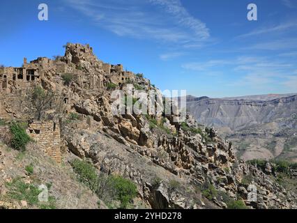 Ruines de l'ancien village abandonné de Gamsutl avec des murs de pierre de construction sur la falaise de pente de montagne contre le ciel bleu le jour ensoleillé Banque D'Images
