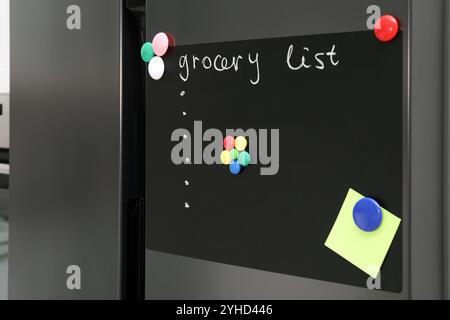 Tableau magnétique avec liste d'épicerie et note sur le réfrigérateur dans la cuisine Banque D'Images
