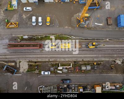 Vue aérienne d'un chantier de construction avec un train jaune circulant sur les rails, à côté d'une route avec des voitures, machine de bourrage, Hermann Hessebahn, Altheng Banque D'Images
