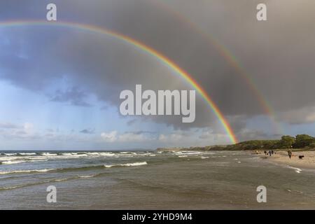 Ciel avec des nuages de pluie et un double arc-en-ciel avec des couleurs intenses et la bande d'Alexandre sur la côte de la mer Baltique avec surf près de Sehlendorf à Schl Banque D'Images