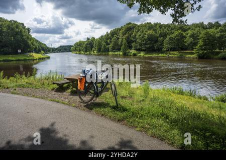 Un vélo se trouve sur une piste cyclable à côté d'une rivière paisible dans la nature, tour à vélo le long des EMS et Emsaltarm-Roheide Banque D'Images