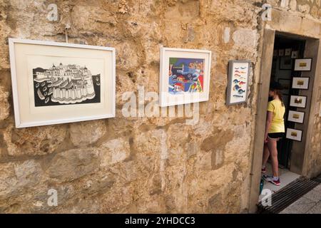 Jeune fille touristique âgée de 9 ans entre dans une boutique de cadeaux vendant des souvenirs des chambres dans le mur de la ville / murs de la vieille ville de Dubrovnik, Croatie. (138) Banque D'Images