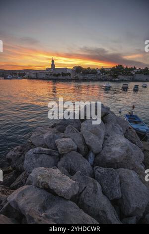 Ville sur une côte, avec une fortification en pierre un port avec une vue sur le coucher du soleil. Photo de paysage de la ville de Krk, Croatie, Europe Banque D'Images