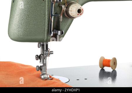 Machine à coudre avec tissu orange et bobine de fil isolé sur blanc Banque D'Images