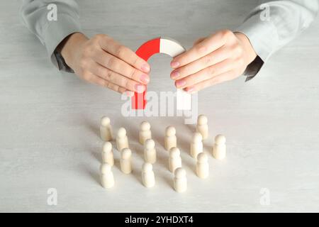 Femme avec aimant attirant des figures humaines en bois à la table lumineuse, gros plan Banque D'Images