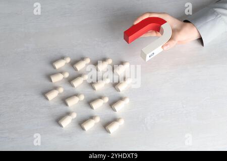 Femme avec aimant attirant des figures humaines en bois à la table lumineuse, au-dessus de la vue Banque D'Images