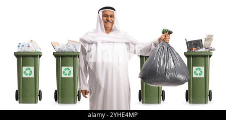 Homme arabe mature tenant un sac à déchets en plastique devant des bacs de recyclage isolés sur fond blanc Banque D'Images