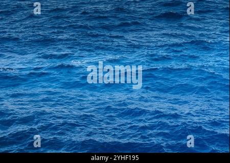 Le soleil se reflète sur l'océan bleu profond, créant un jeu de lumière fascinant sur les vagues ondulantes. Banque D'Images