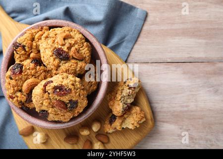 Délicieux biscuits à l'avoine avec raisins secs et noix sur la table en bois, vue de dessus. Espace pour le texte Banque D'Images