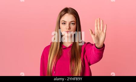 Arrêter le mouvement. Une jeune fille adolescente très stricte à capuchon rose lève la main Banque D'Images