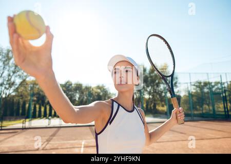 Joueuse de tennis en vêtements blancs s'exerçant sur les courts de tennis Banque D'Images