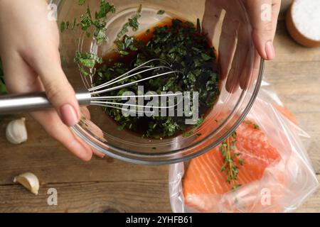 Femme avec marinade de soja et filet de saumon dans un sac en plastique à la table en bois, vue de dessus Banque D'Images