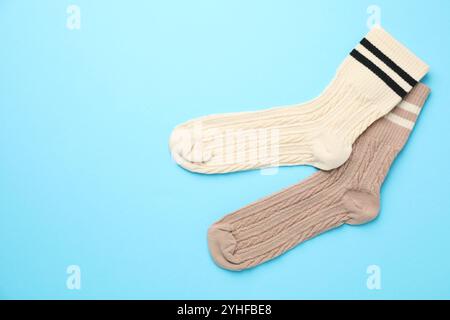 Différentes chaussettes confortables sur fond bleu clair, pose plate. Espace pour le texte Banque D'Images